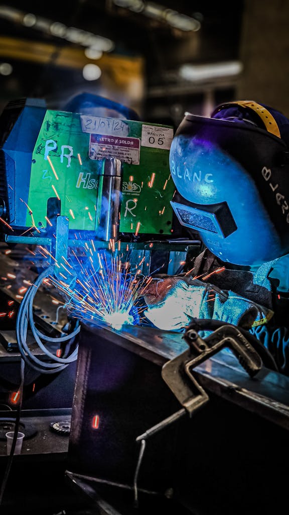 Close-up of welder at work, creating vivid sparks in an industrial setting. Safety gear worn.